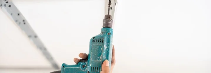 Hand benutzt Bohrmaschine an Decke