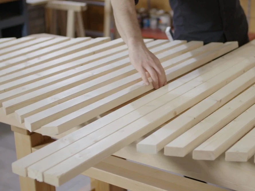 Person legt Holzlatten auf einen Tisch