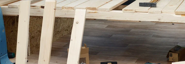 Holzlatten werden mit einem Akkuschrauber auf einem Holzboden befestigt.