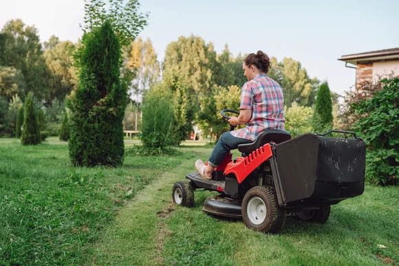 Person mäht Rasen mit Aufsitzmäher
