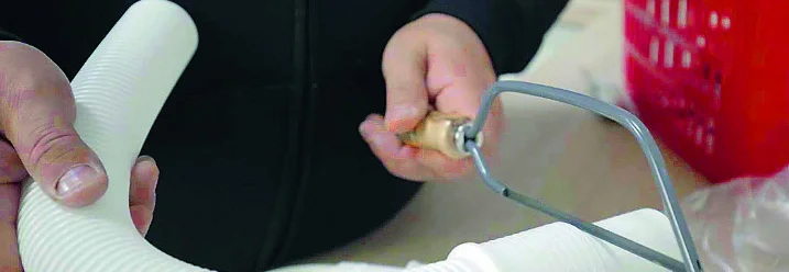 Person kürzt Siphon mit Säge