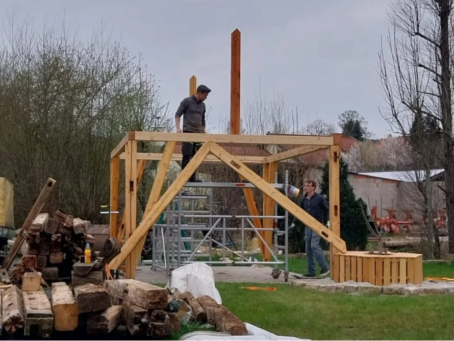 Zwei Personen bauen ein Gartenhaus aus Holz