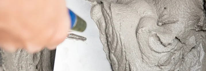 Hand verteilt grauen Mörtel mit Kelle