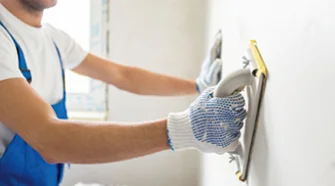 Person schleift Wand mit Schleifklotz