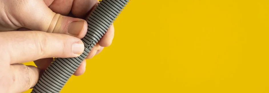 Hände halten einen gebrochenen Schlauch