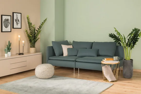 Modern eingerichtetes Wohnzimmer mit blaugrünem Sofa und vielen Pflanzen.