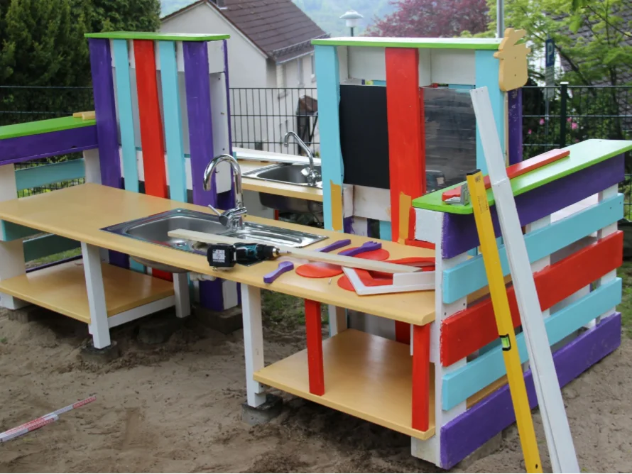 Eine farbenfrohe Spielküche aus Holz mit einem Akkuschrauber.