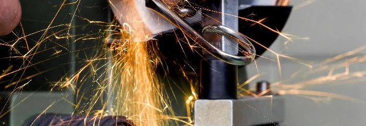 Person schärft Schere an Schleifmaschine