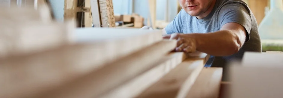 Person stapelt Holzbretter