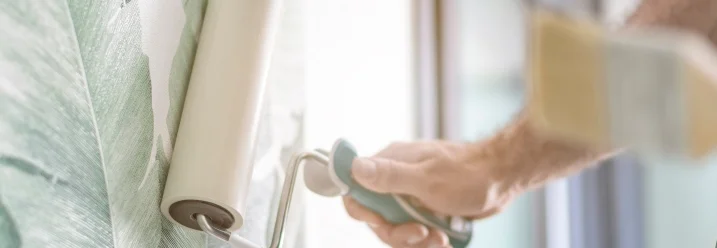 Person streicht Tapete mit Rolle glatt