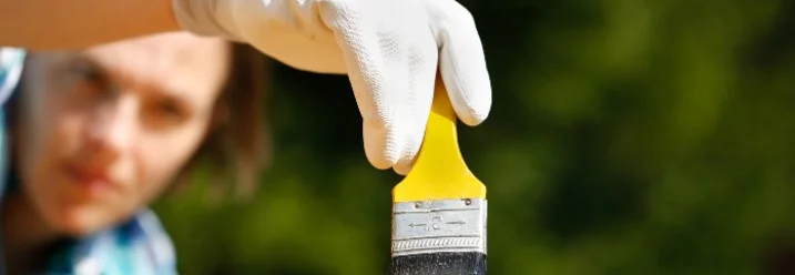 Person streicht Holz mit Pinsel