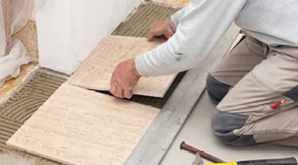 Person verlegt Fliesen mit Gummihammer