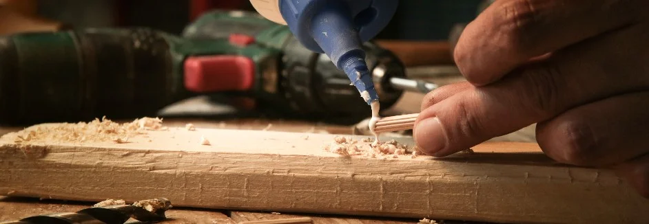 Person trägt Klebstoff auf Holz auf