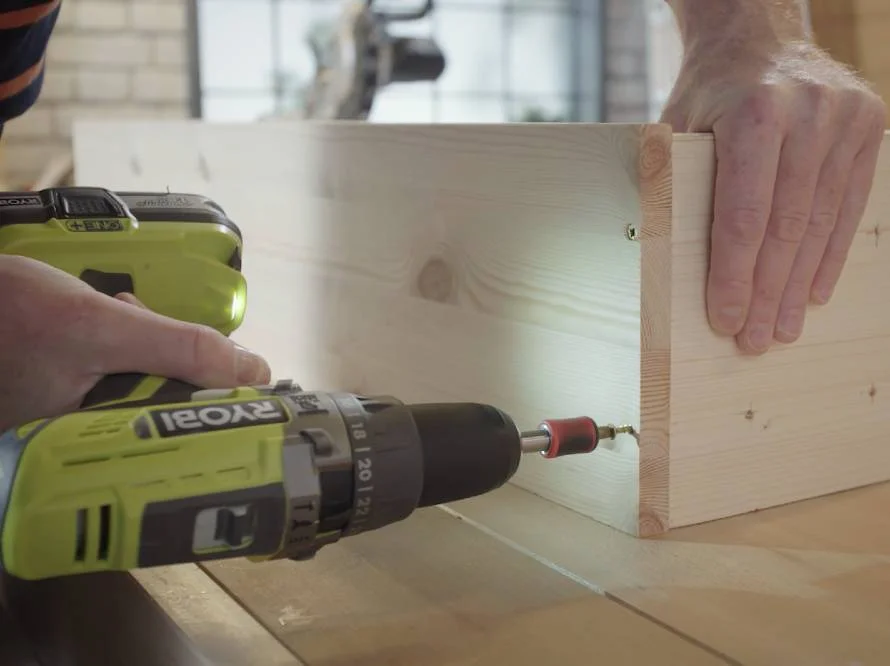 Person verschraubt Holzbretter mit Akkuschrauber