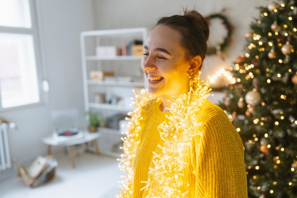 Frau lacht mir weihnachtlicher Beleuchtung um den Hals