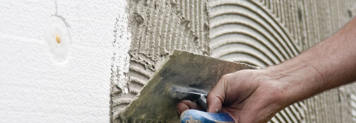 Person trägt Putz mit Kelle auf