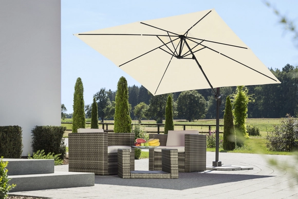 Eine Sitzgruppe aus Polyrattan mit einem Ampelschirm steht auf einer Terrasse.