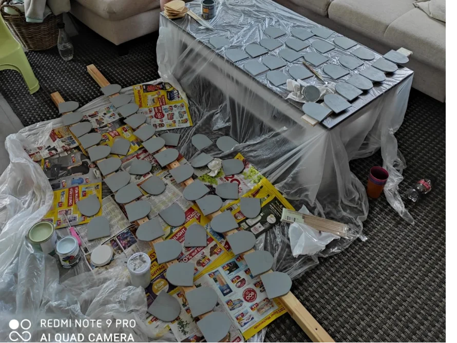 Viele graue Holzteile auf einer mit Folie ausgelegten Fläche