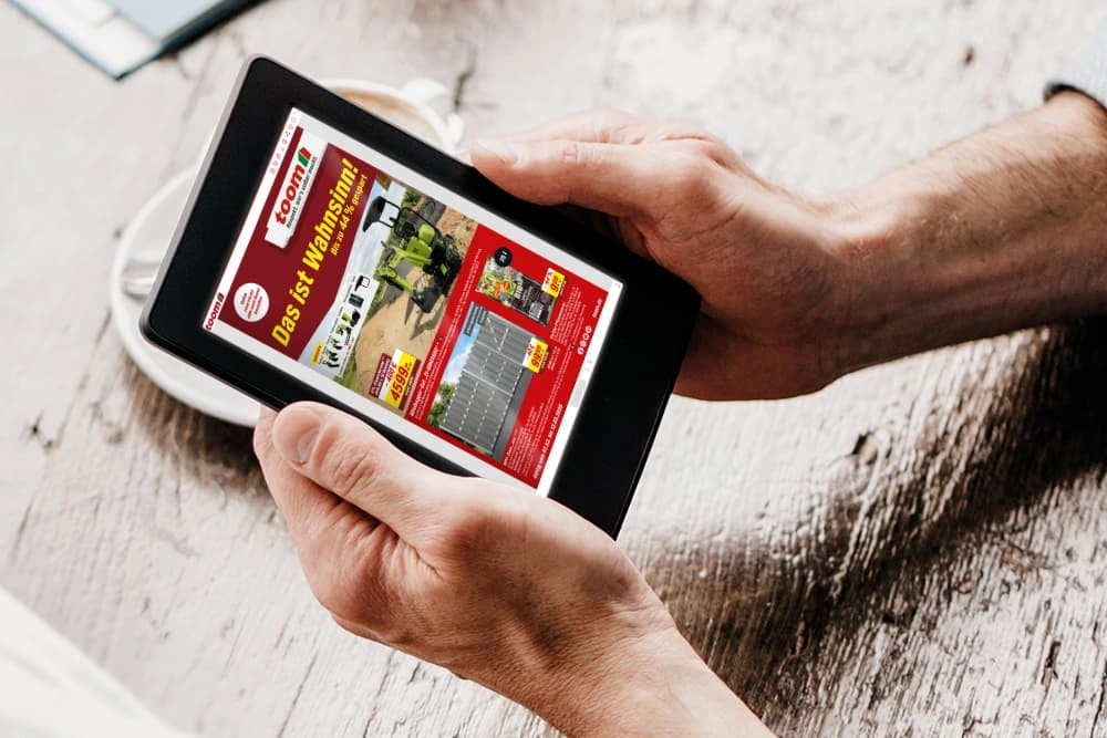 Eine Person hält ein Tablet in den Händen und schaut einen digitalen Prospekt an.