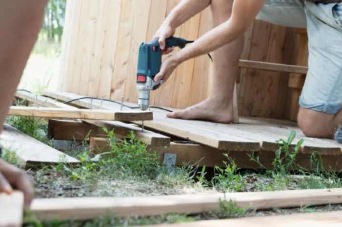 Person baut Holzterrasse mit Akkuschrauber