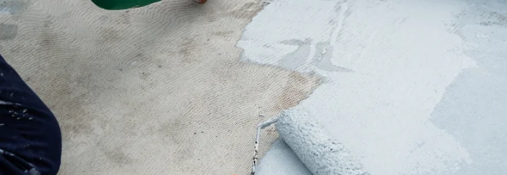 Person streicht graue Farbe auf Boden