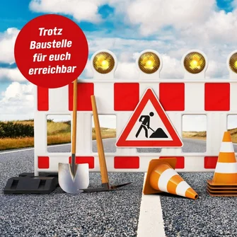 Trotz Baustelle für euch erreichbar: Baustellenabsperrung mit Warnleuchten, Werkzeug und Pylonen auf einer Straße.