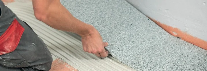 Person verlegt graue Bodenfliese