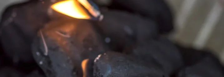 Hand zündet Grillkohle mit Streichholz an