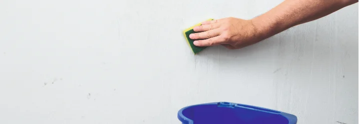 Person reinigt Wand mit Schwamm