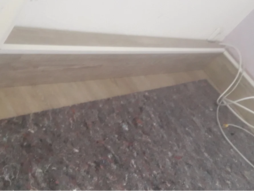 Holzsockel an Wand und Teppich