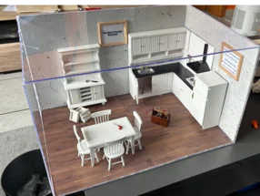 Modell einer weißen Küche mit Esstisch und Werkzeugkiste