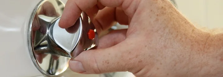 Hand dreht an einem Wasserhahn.