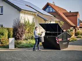 Person wirft Eimer in Container