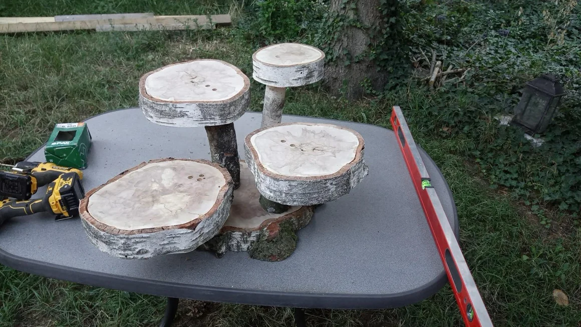 Eine selbstgebaute Etagere aus Birkenholzscheiben mit Werkzeug auf einem Gartentisch.