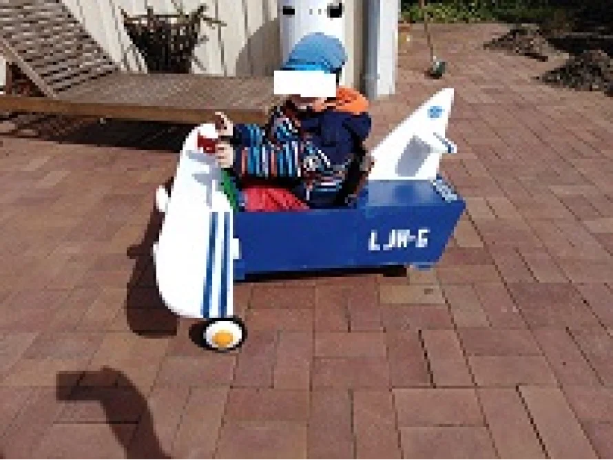 Kind in einem blauen Spielzeugflugzeug