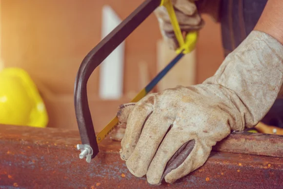 Handwerker sägt Metall mit Bügelsäge
