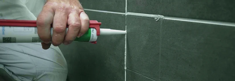 Person trägt Dichtmittel auf Fliesen auf