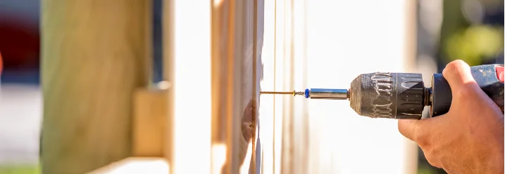 Person baut einen Holzzaun mit Akkuschrauber