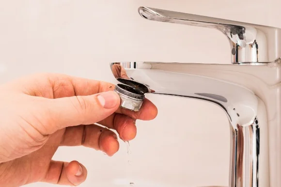 Hand hält verkalkten Siebeinsatz