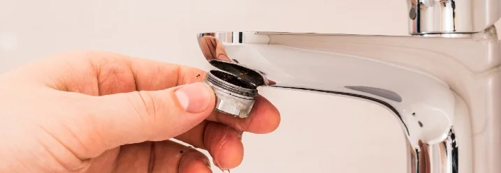 Hand hält verkalkten Siebeinsatz