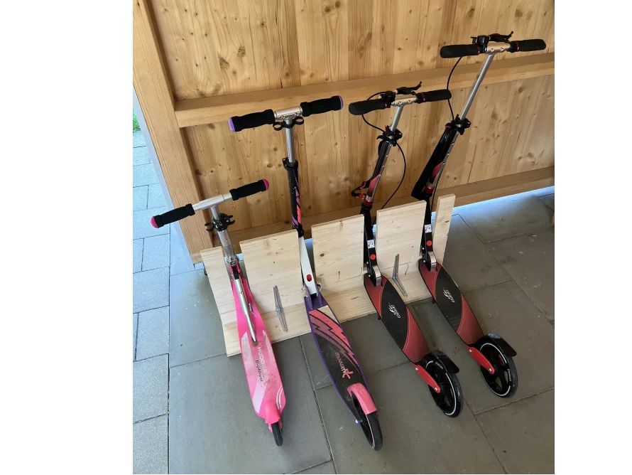 Vier Tretroller stehen an einer Holzkonstruktion