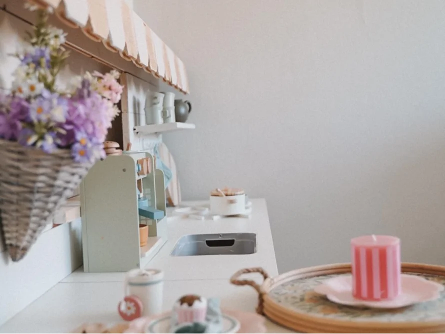 Pastellfarbene Spielküche aus Holz mit Blumen und Zubehör.