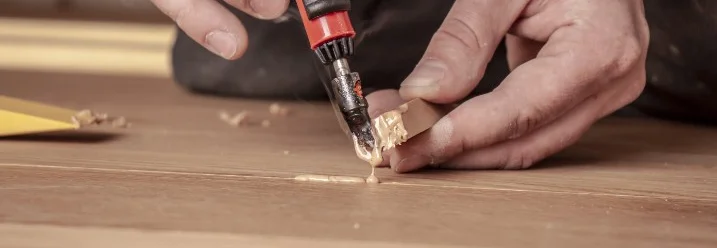 Person repariert Holztisch mit Werkzeug.