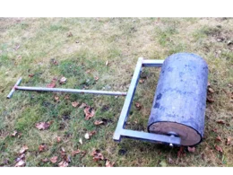 Eine Rasenwalze liegt auf einem Rasen.