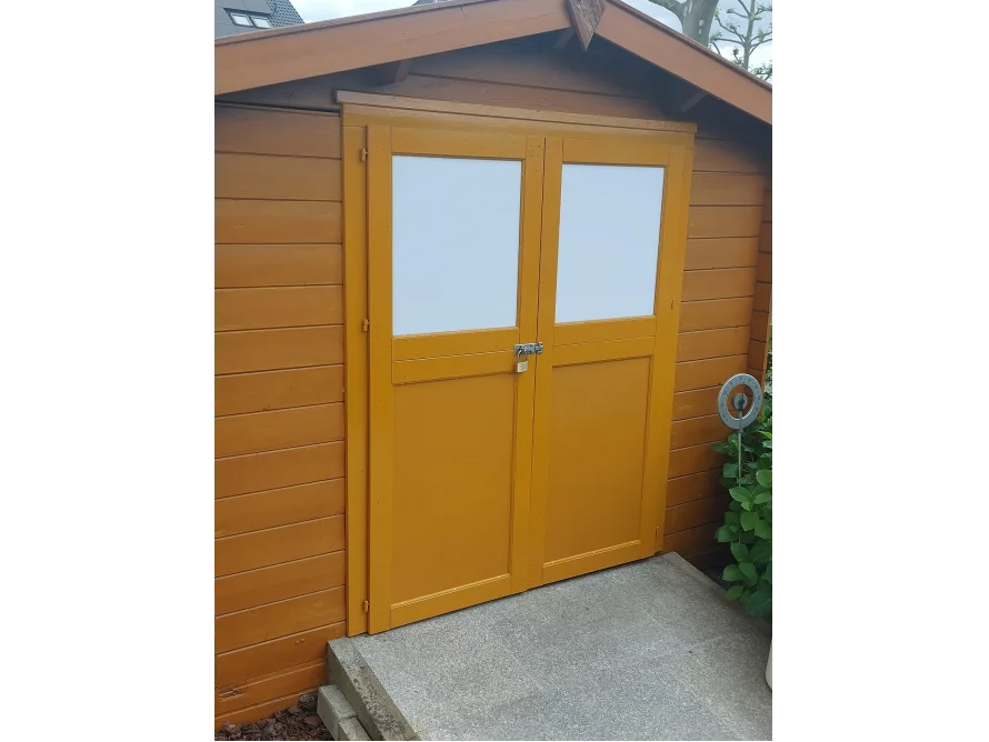 Gelbes Gartenhaus mit weißen Fenstern