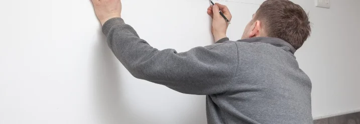 Person misst mit einem Zollstock eine Wand ab