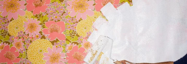 Person überstreicht Blumentapete mit Rolle