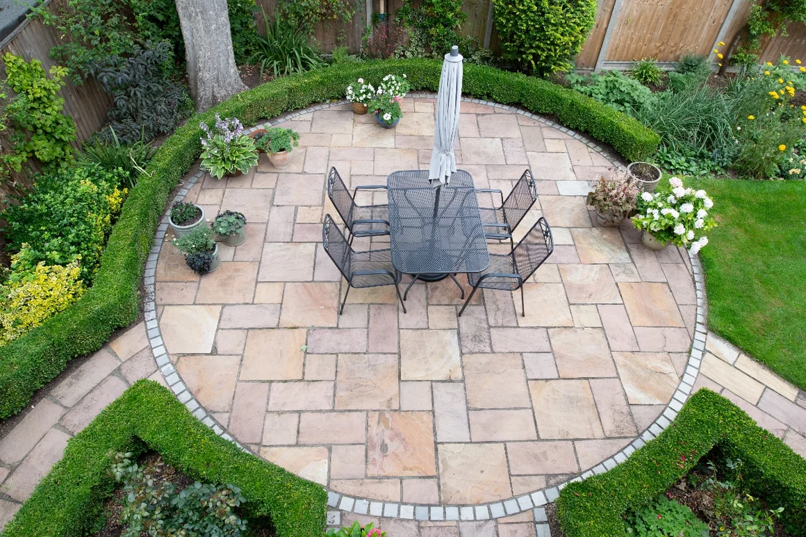 Runde Terrasse mit Gartenmöbeln und Sonnenschirm