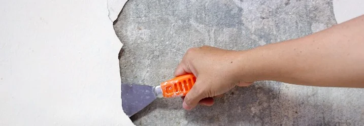 Hand entfernt Farbreste mit Spachtel