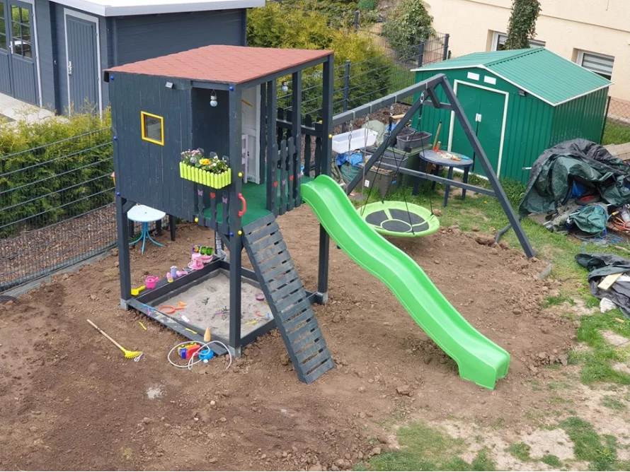 Spielplatz im Garten mit Spielhaus, Schaukel und Rutsche